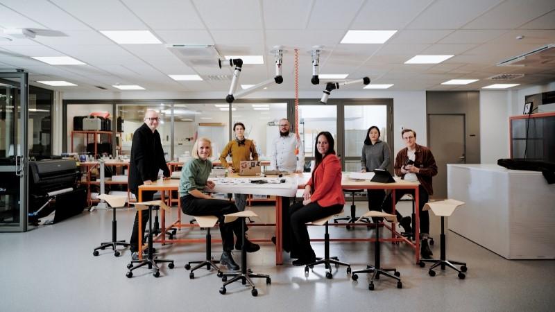Team looking at the camera around table in Vaisala R&D house Maker Lab