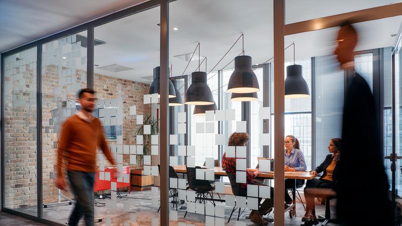 A group of business professionals walk down the corridor next to their office